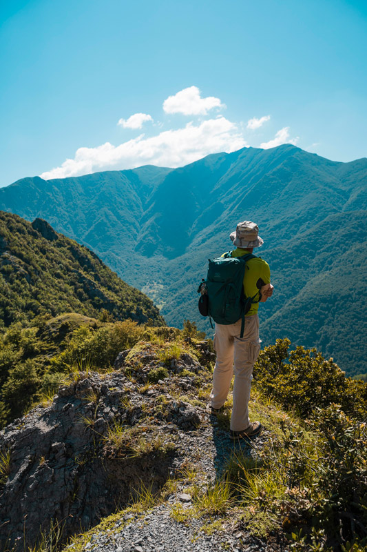 Escursionista tra i monti del parco nazionale del pollino, tra verdi ventieri un cielo azzurro, sul monte trincero di Verbicaro che si affaccia sul monte Cozzo del Pellegrino - Trekking in Calabria