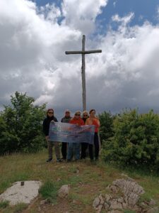 foto di gruppo di escursionisti con alle spalle una croce
